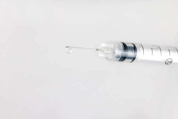Macro shot of a syringe with clear liquid and droplet, COVID-19 vaccine - Photo, Image
