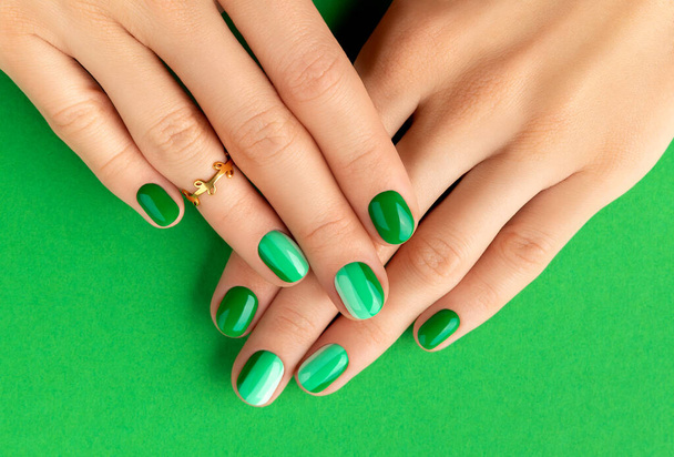 Beautiful groomed woman's hands with spring summer nail design on green background. Manicure, pedicure beauty salon concept. - Photo, Image