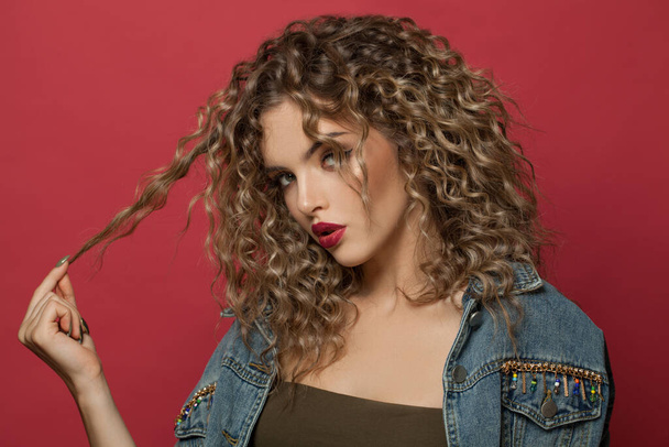 Nice woman with curly hair posing on red background - Fotoğraf, Görsel