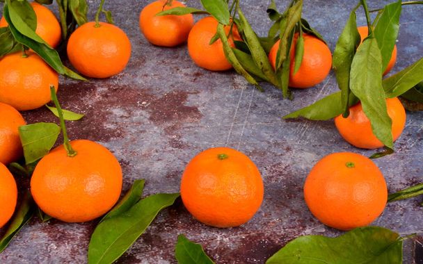 Fresh mandarin, clementine, tangerine with green leaves on a rusty surface background - Photo, Image