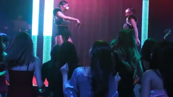 Grupo de personas bailan en discoteca al ritmo de la música de DJ en el escenario - Imágenes, Vídeo