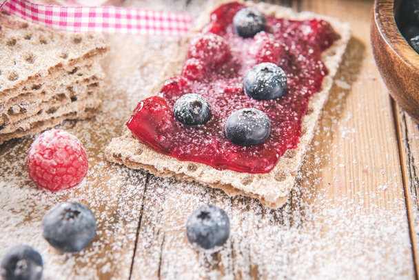 Sweet spread with berries on toast over wooden table. Tasty meal  - Photo, Image