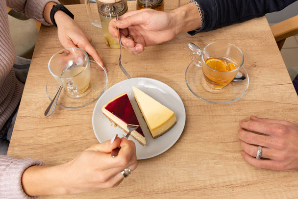 les mains d'un homme et d'une fille qui ont droit à un gâteau au fromage et boivent du thé aux fruits dans un café. concept de café  - Photo, image