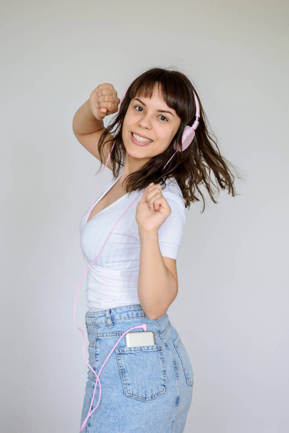 close up photo of a happy brunette with pink headphones in white blouse and denim skirt  - Fotoğraf, Görsel