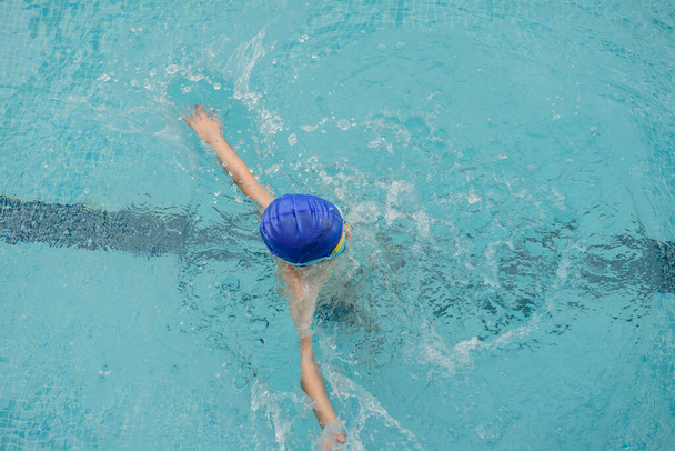 ylhäältä näkymä 7-vuotias poika pelaa ja ui uima-altaassa - Valokuva, kuva