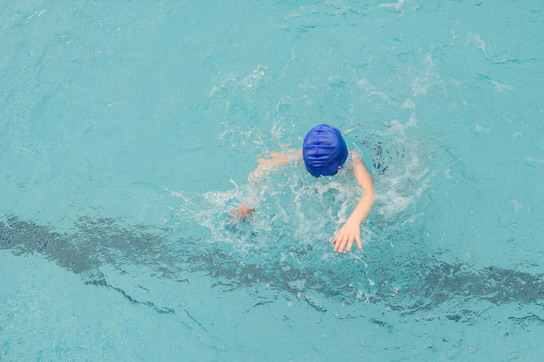 вид сверху на 7-летнего мальчика, играющего и плавающего в бассейне - Фото, изображение
