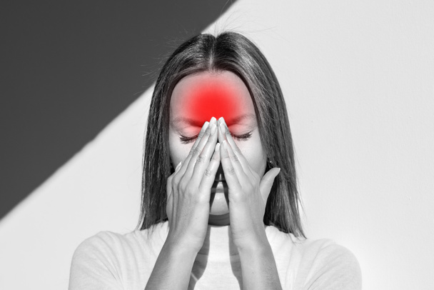 Woman feeling unwell, painful headache because of sinus ache, sinusitis, sinus pressure. Sad woman holding her nose and head because sinus pain. Black and white photo. High quality photo - Photo, Image