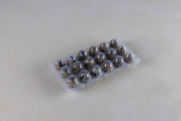 Перепелиные яйца в пластиковой упаковке, пластиковая оболочка для защиты яиц, на бежевом фоне. Яйца на рынке - Фото, изображение