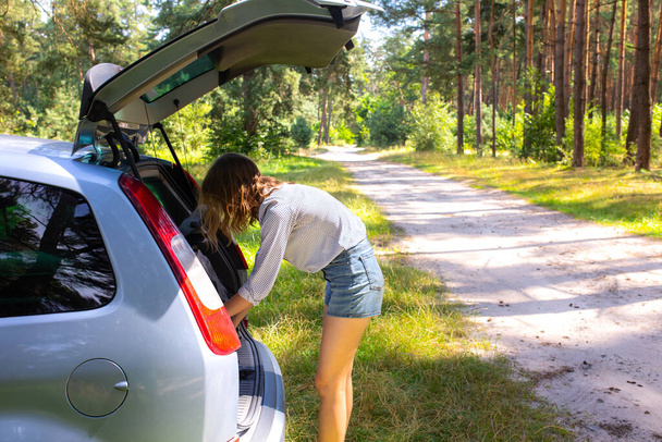 Woman is repairing the car in the forest. Broken vehicle. - Photo, Image