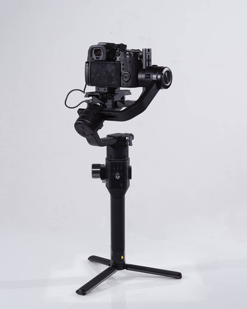 Tükrözi professzionális kamerák egy gimbal kamera stabilizátor. Videókamera Gimbal Stabilizációs állványrendszer fehér háttérrel. Gimbals stabilizáló rendszer tükör nélküli kamerával. - Fotó, kép