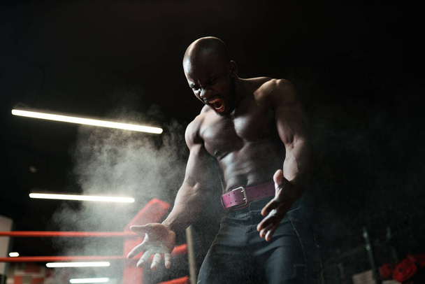 bodybuilder athlete clapped his hands and sprayed magnesium or talcum powder before lifting the barbell. White dust from magnesium - Foto, immagini