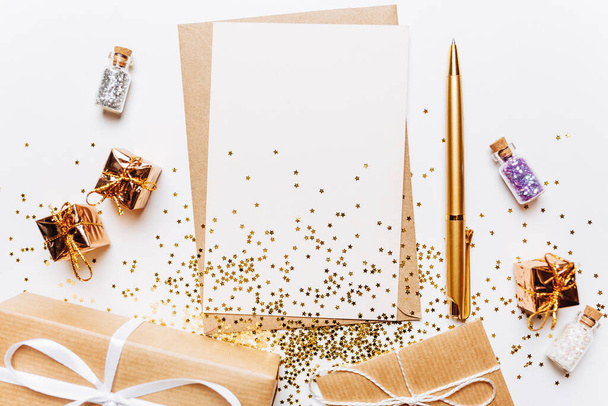 Blank note with envelope, gifts, pen and gold glitter stars on white background - Foto, Imagen