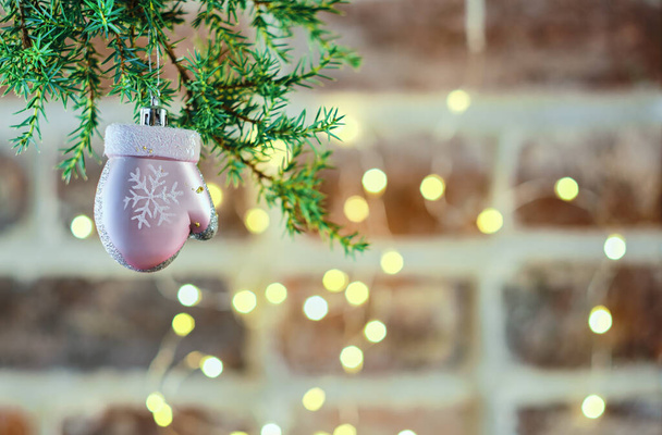 ガーランドで飾られたレンガの壁の背景におもちゃでクリスマスツリーの枝を持つお祭りのクリスマスカード、選択的な焦点。バナーやポストカード、クローズアップのためのクリスマステンプレート - 写真・画像