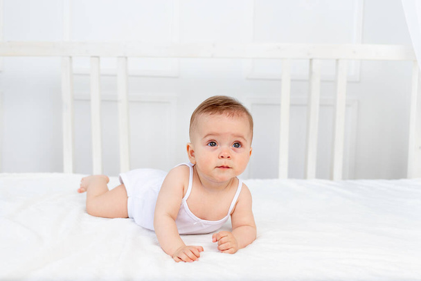 the baby is sitting in a crib in a bright room - Photo, Image