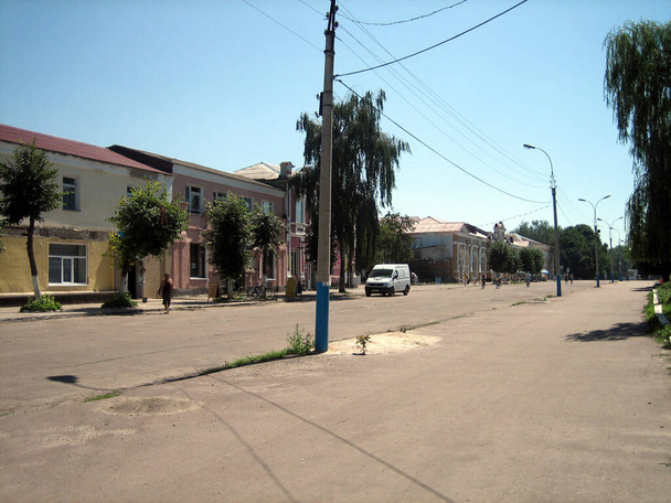 A wide, deserted square in a small provincial city in Russia. Gray asphalt surrounded by several two-storey houses in the centre of the city. - Valokuva, kuva