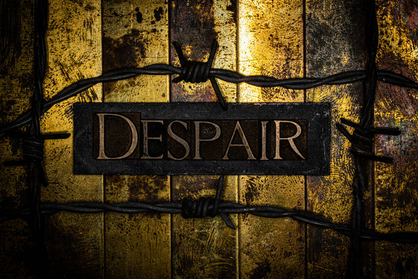 Despair text with barbed wire on textured gold and copper surface - Photo, Image