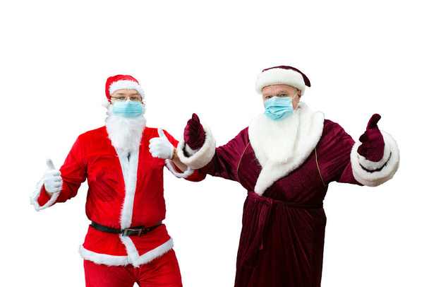 Ded Moroz de Rusia y Santa Claus en máscaras médicas. Las manos de Santa muestran buen signo. Aislar. - Foto, Imagen