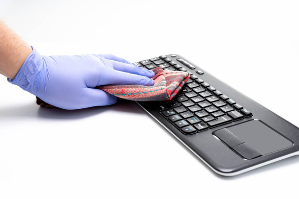 Kesztyű kéz tisztítása számítógép billentyűzet fehér háttér - Fotó, kép