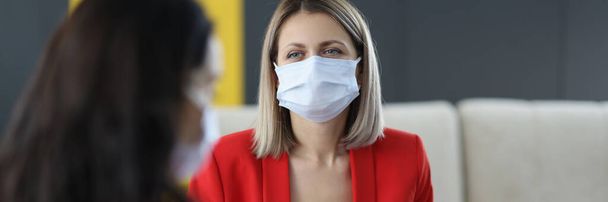 Kobiety w medycznych maskach ochronnych komunikują się w biurze. - Zdjęcie, obraz
