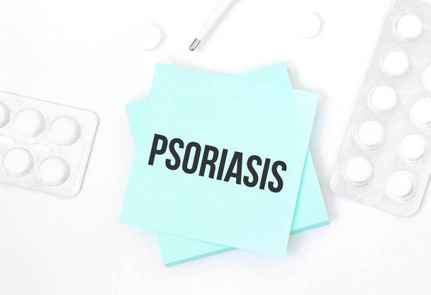 Blue card with text PSORIASIS on a table with a pills and pencil, medical concept, top view - Fotografie, Obrázek