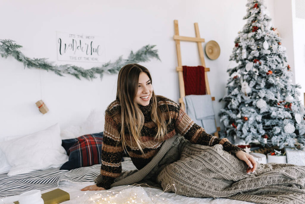 Young caucasian woman relaxing on a bed at home in Christmas holidays. High quality photo - Foto, Bild