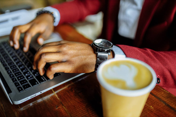 african american man getting online education and drinks coffee to go frop paper eco cup - 写真・画像