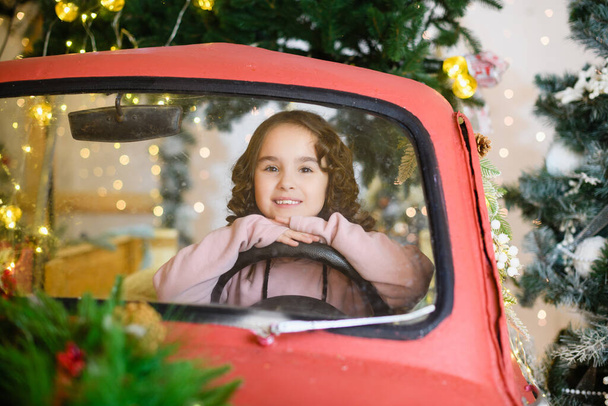 Κορίτσι κάθονται στο αυτοκίνητο για τα Χριστούγεννα φόντο - Φωτογραφία, εικόνα