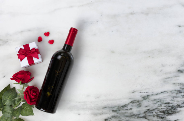Happy Valentines Day mit schönen Rosenblüten und Rotweinflasche plus Geschenkbox auf Naturmarmor  - Foto, Bild