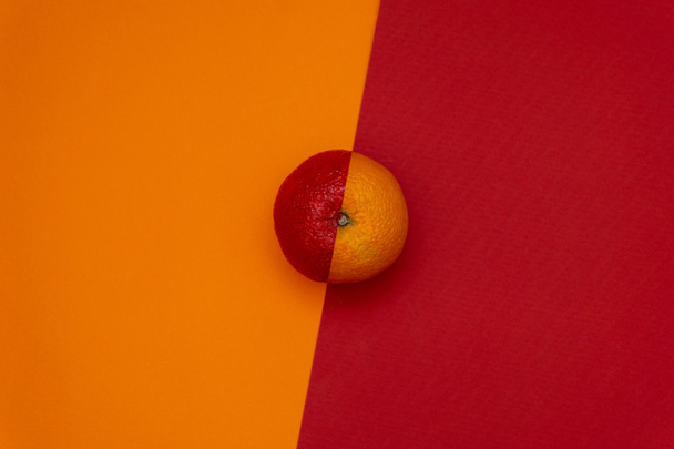 Half red orange on dual tone background. Flat lay. Minimal food concept - Valokuva, kuva