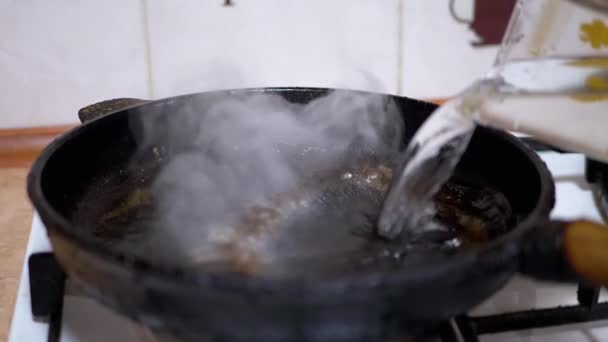 Pouring Water from Glass in Hot, Greasy Skillet. Boiling Liquid, Evaporation - Footage, Video