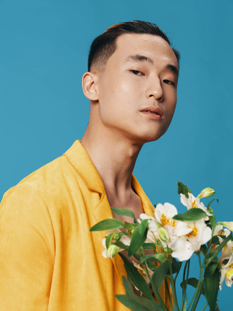 Um cara bonito de aparência asiática segurando um buquê de flores brancas vista cortada - Foto, Imagem