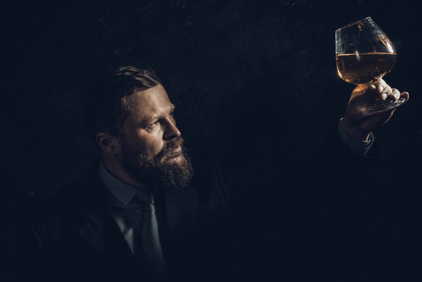 Solid confident bearded man in suit with glass of whisky - Фото, изображение