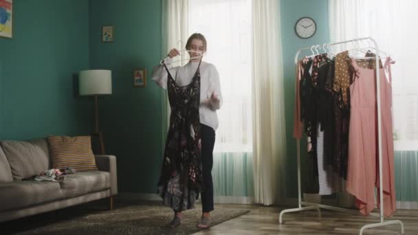 Девушка в белом свитере разбрасывает одежду по комнате - Кадры, видео