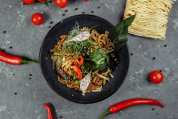 Sült tészta és zöldség keverve, fekete tálban. Finom, tápláló ázsiai ételek. - Fotó, kép