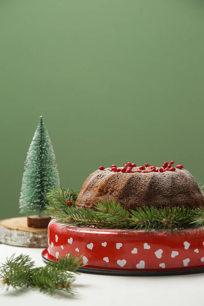 Bundtentaart versierd met rode bessen met kleine kerstboom. Eenvoudige en minimalistische inrichting voor de wintervakantie. - Foto, afbeelding