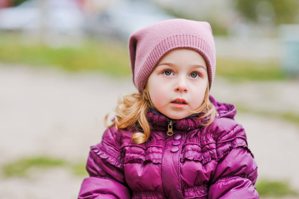 Active little girl on playground. Girl little child in the playground. Child in a purple jacket - Φωτογραφία, εικόνα