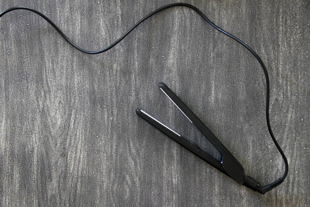 Hair straightener, stylist's tool on vintage wooden gray background - Φωτογραφία, εικόνα