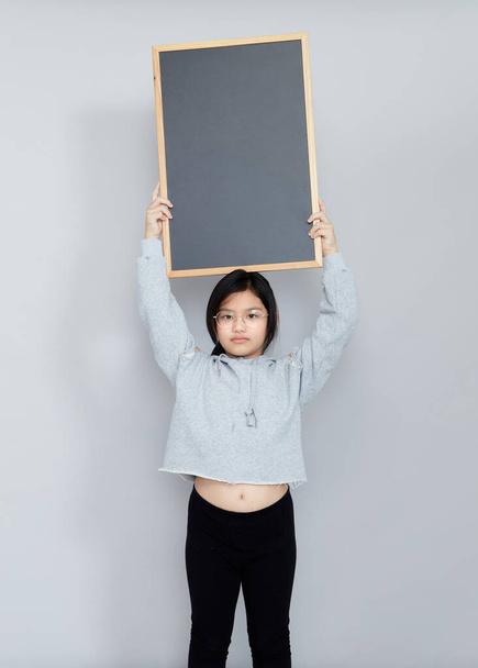 A little girl holds a blank chalkboard place for notification. Read this notification. Informing about the event. Cute schoolgirl with blackboard. Advertisement. - Photo, Image