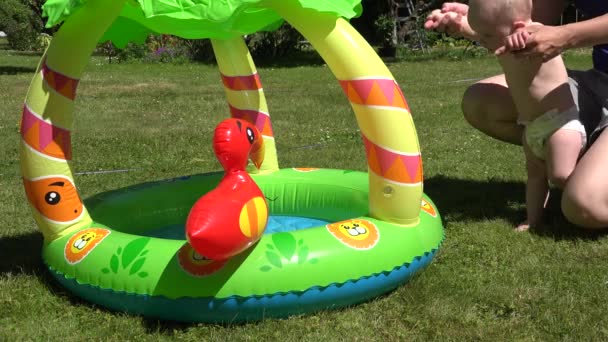 Mother habituate child to rubber inflatable water pool outdoor . 4K - Footage, Video