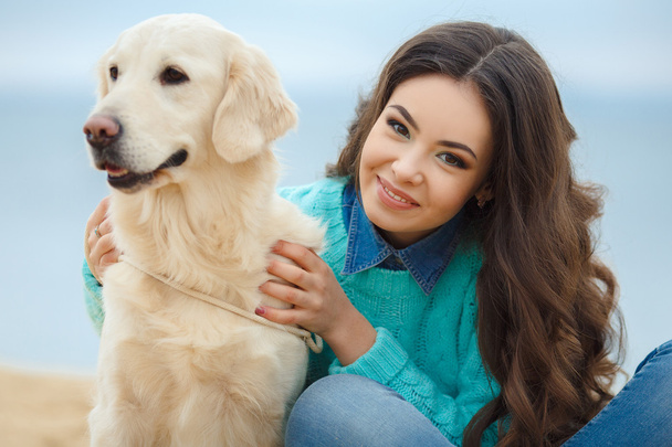 Portrait of beautiful young woman playing with dog on the sea shore - Foto, Bild