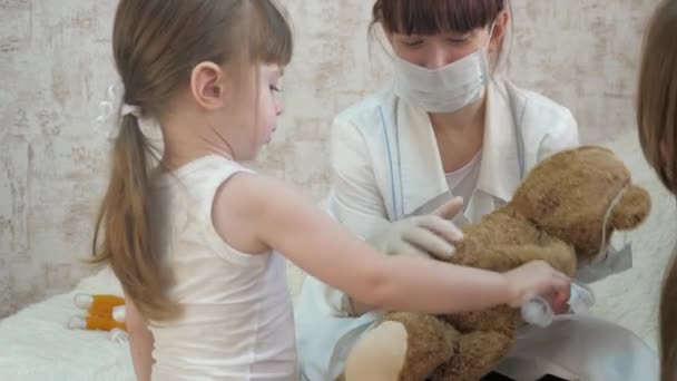 Çocuklar doktorculuk oynuyor, hemşire, aşı ile tedavi ediliyor. Küçük çocuk oyuncak hayvanlara iğne yapıyor. Küçük kız hastanede annesiyle oynuyor. Sağlıklı kız ve oyuncak ayı. Çocuk hastanede oynuyor.. - Video, Çekim