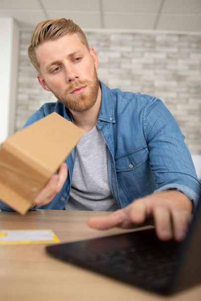 man with laptop and cardboard box at home - Foto, Bild