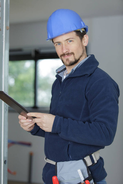 builder with a tablet for papers - Foto, afbeelding