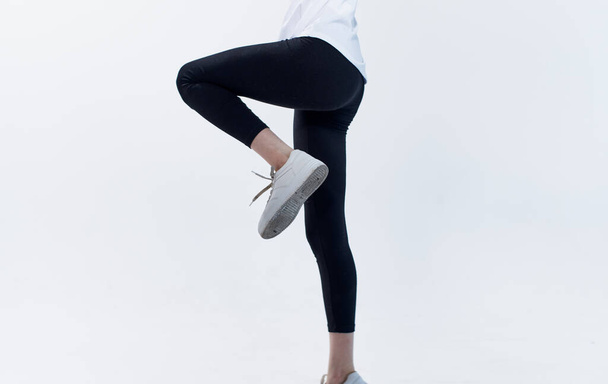 Γυναίκα σε αθλητικά ρούχα και αθλητικά παπούτσια σε ελαφρύ φόντο γυμναστήριο - Φωτογραφία, εικόνα