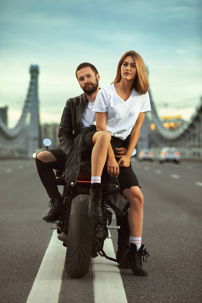 Любовь и романтическая концепция. Красивая пара на мотоцикле в середине дороги на мосту, на двойном твердом - Фото, изображение