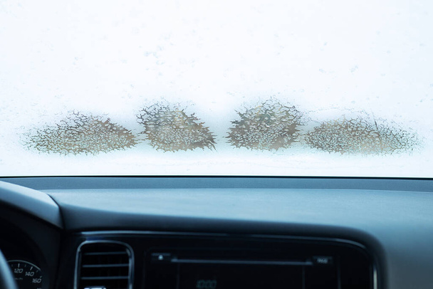 замороженное лобовое стекло автомобиля зимой, внутри автомобиля, низкая температура, таяние льда на окне, работающий климат-контроль. Крупный план с копировальным пространством - Фото, изображение