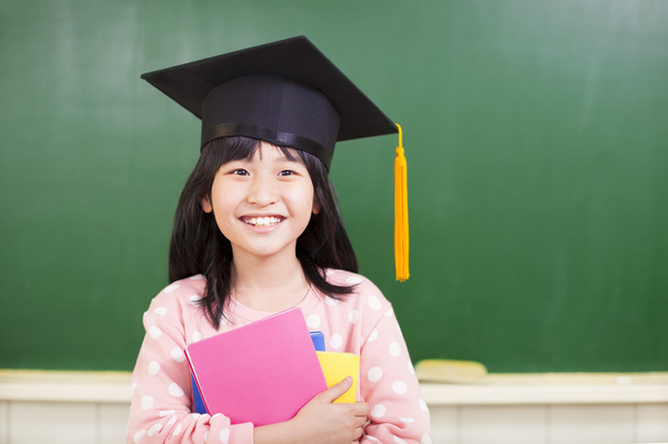 smiling girl wear a graduation hat and holding books - Фото, изображение