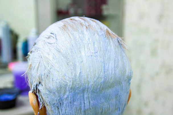 jonge vrouw verft zijn haren in schoonheidssalon - Foto, afbeelding