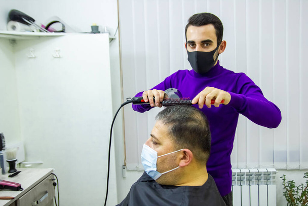 hairdresser is cutting clients hair in barber shop - Fotó, kép