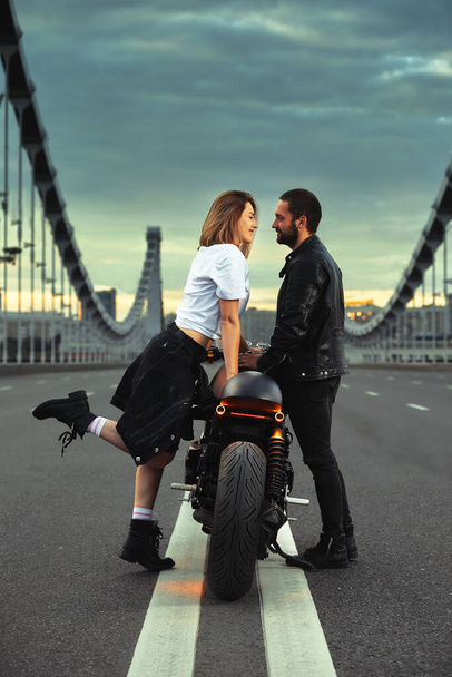 Amour et concept romantique. Beau couple à moto se tient en face l'un de l'autre au milieu de la route sur le pont, sur double solide - Photo, image